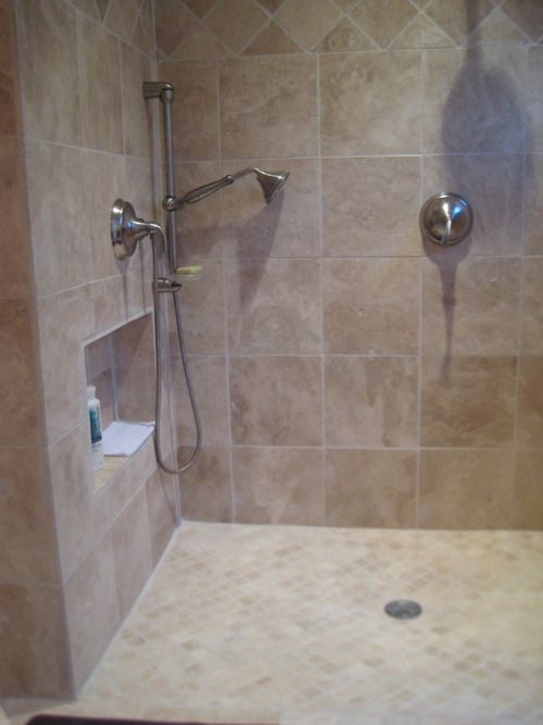 this image shows the addition of a handheld shower, along with the overhead shower on the adjacent wall and includes a niche for shower accessories