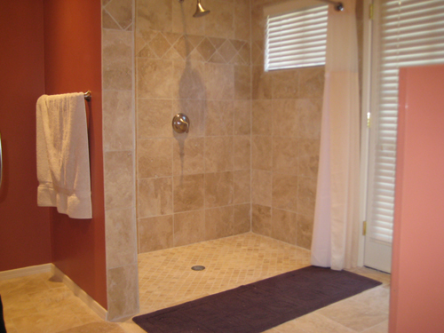 the newly remodeled bathroom shows all new tile flooring, and walls with no curb at the shower entry